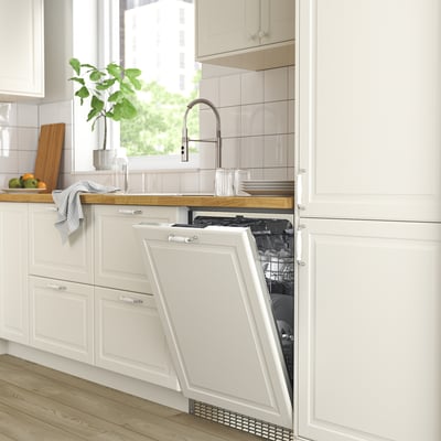 Modern kitchen with open white FLÅBODA dishwasher, silver tap, wooden countertop, and green plant.