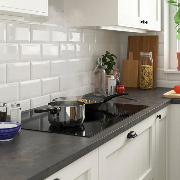 Modern kitchen with FLACKSTA induction hob, wooden boards, and minimalist backsplash.