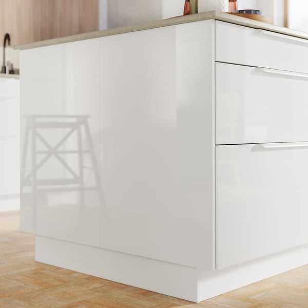Modern kitchen island with white glossy cabinets and light wooden floor.