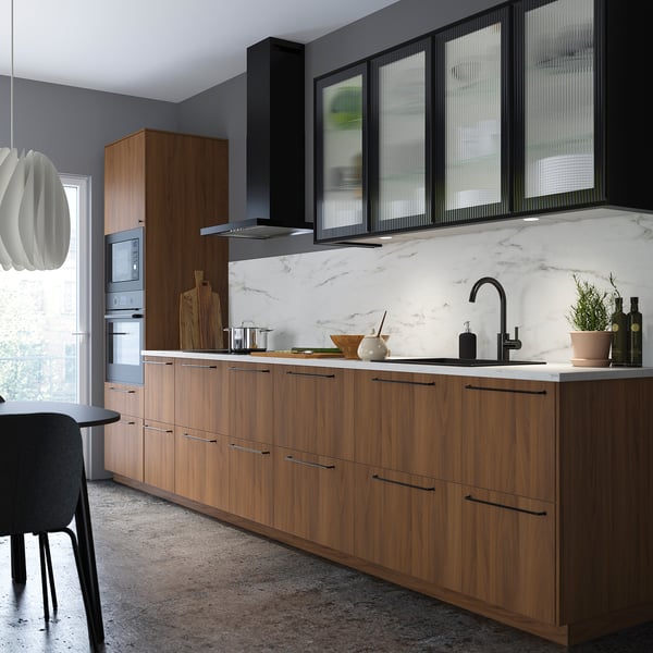 Modern kitchen with walnut FÖRBÄTTRA cabinets, black handles, and marble backsplash.