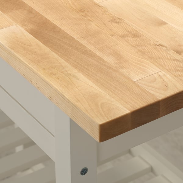 Close-up of FÖRHÖJA kitchen island: smooth, light birch top with visible grain, supported by sturdy white legs, showcasing high-quality craftsmanship.