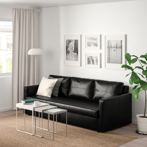 Contemporary living room with black FRIHETEN sofa, modern tables, and plant.