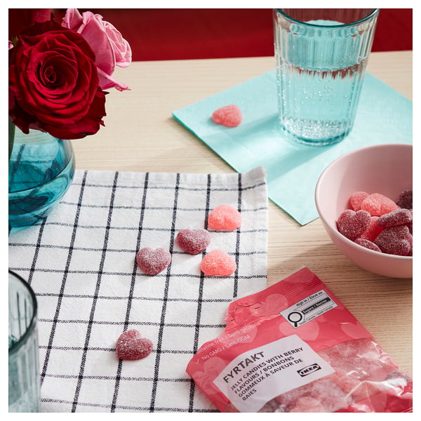 Open ikea candy bag on table with hearts, rose, and bowl.