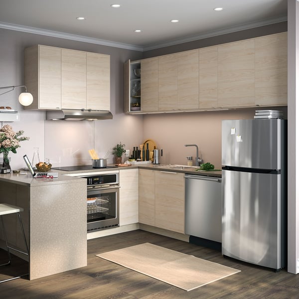 Modern kitchen with light wood cabinets, stainless steel appliances, and recessed lighting.