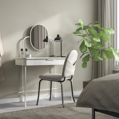 A GRÅFJÄLLET white dressing table with a round mirror, black lamp, and grey chair. It is compact, fitting neatly in the corner of a modern bedroom.