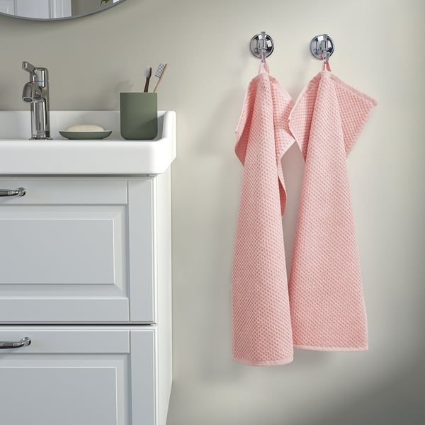Bathroom with wooden vanity, sink, chrome fixture, toothbrushes, pink towels.