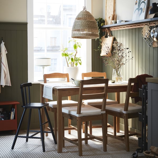 Cosy dining area with wooden HÄGERNÄS set, large pendant light, plant, and decorated shelves.
