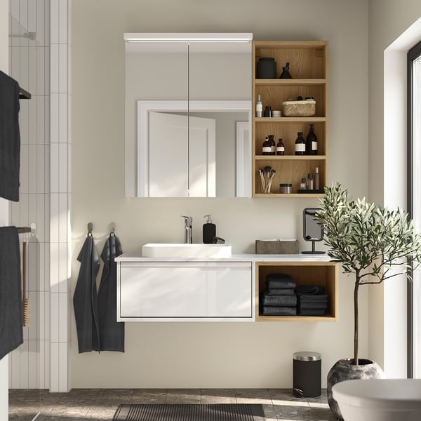 Modern bathroom with light wood hagån cabinet, mirror, towels, and plants.