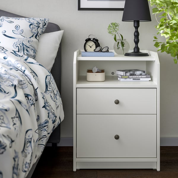 HAUGA bedside table: drawer, shelf, lamp, book, clock. Clean design.
