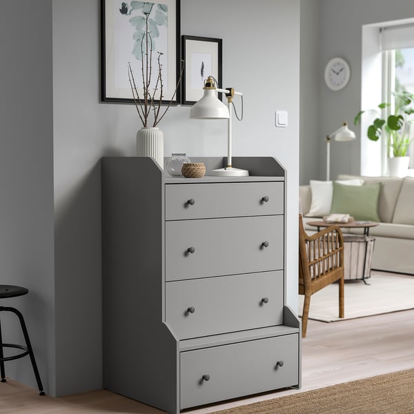 HAUGA grey chest drawer in corner, lamp, vases, near sofa.