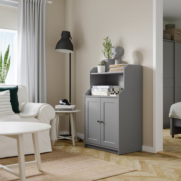 Modern living room with HAUGA grey cabinet, white couch, round table, black floor lamp, and rug.