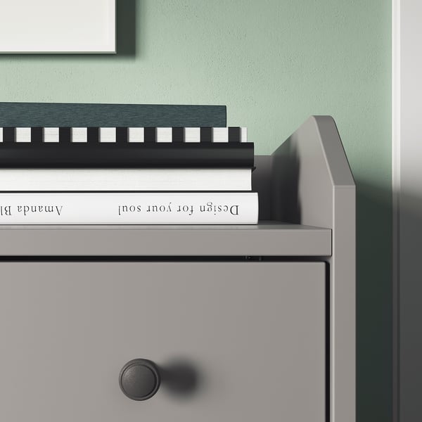 Modern grey HAUGA chest with three stacked books, against green wall.
