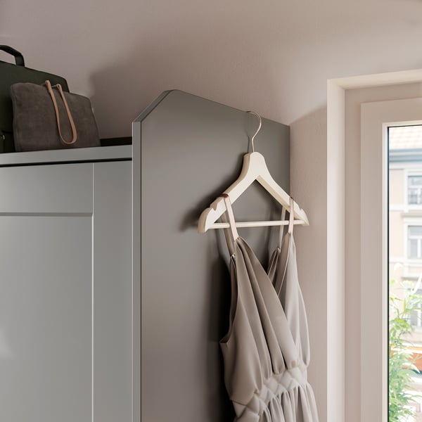 A grey HAUGA wardrobe with a light-colored hanger and a dress.