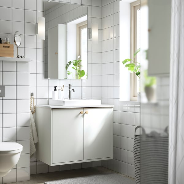 Modern bathroom with white HAVBÄCK vanity, mirror lighting, and plants.