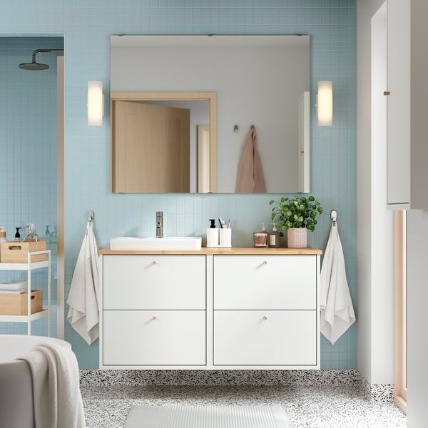 White wall-mounted bathroom vanity with sink, blue walls, mirror, towels, wood countertop, plants.