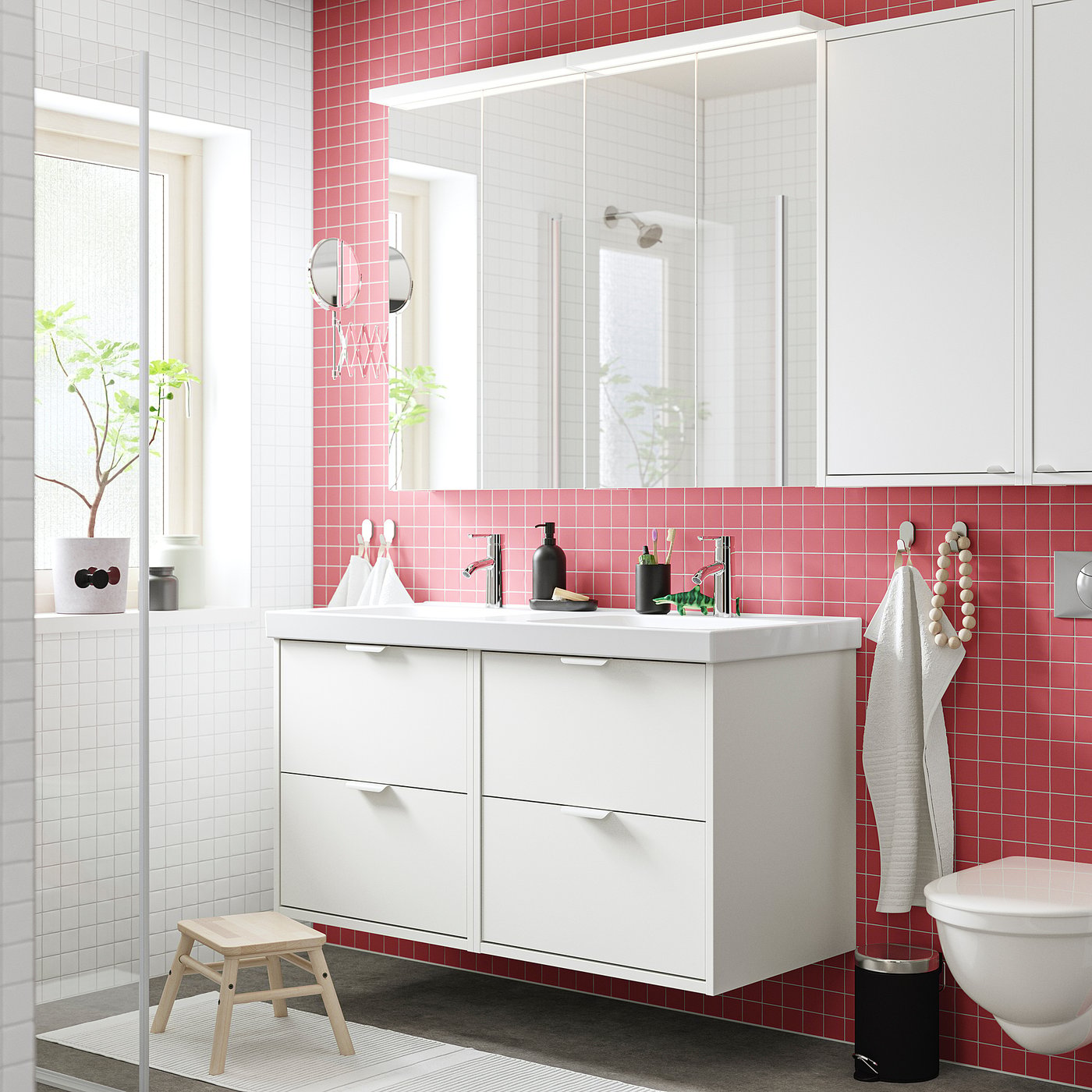 Modern bathroom with white HAVBÄCK vanity, red tiles, grey rug, small stool, and wall-mounted white toilet.