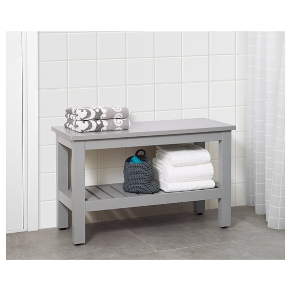 White bathroom bench with folded towels on top and bottom shelf for storage.