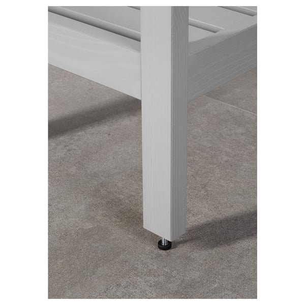 White wooden furniture leg with metal foot on grey carpeted floor.