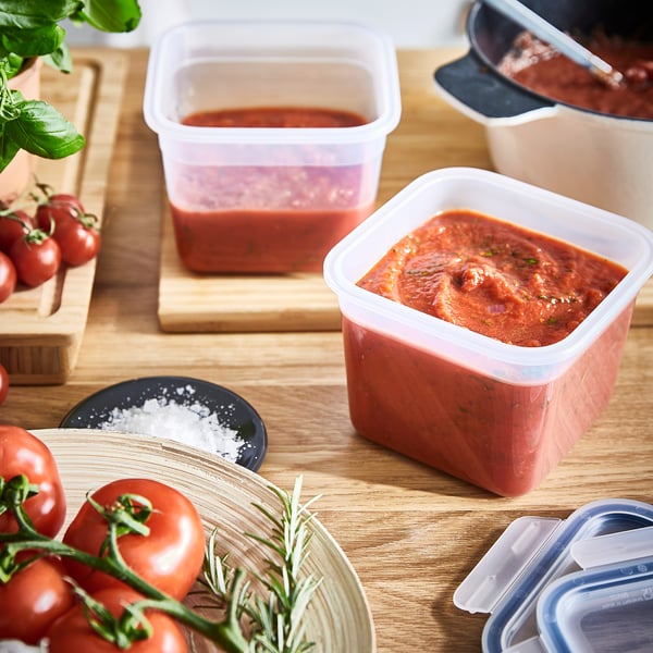 Several plastic containers storing tomato sauce and fresh tomatoes, ideal for preserving leftovers efficiently.