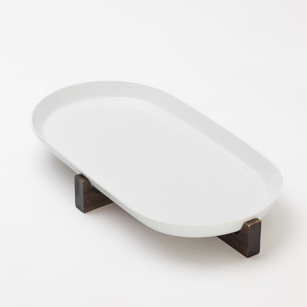 White ikea oval serving dish on dark wood stand.