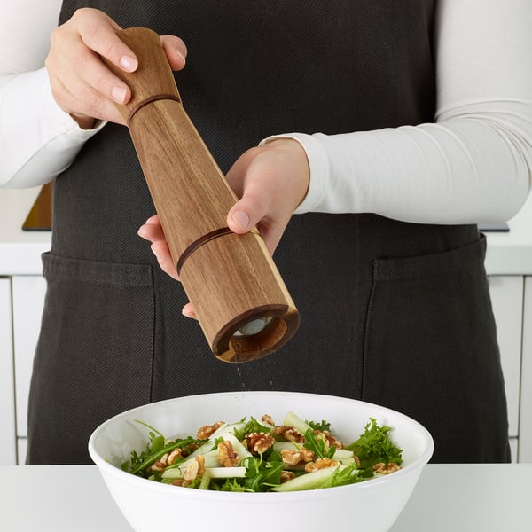 Person seasoning salad with INTRESSANT wooden grinder.