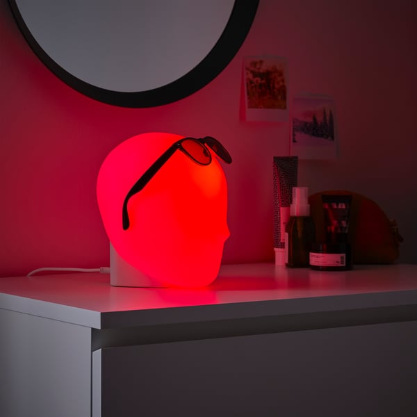 Red led iskarna desk lamp with whimsical head design for creative ambiance.