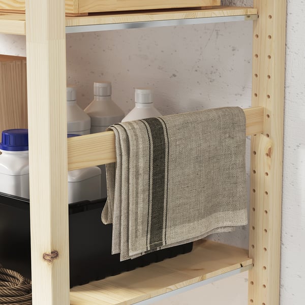 Jaune pine shelf with lined towel, three grey bottles, black plastic bin, blue-lid container on left.