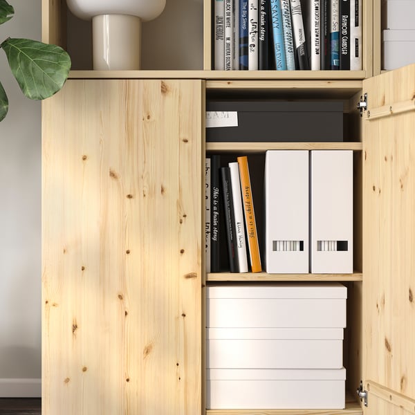 A wooden IVAR storage cabinet with shelves holding books, files, and boxes.