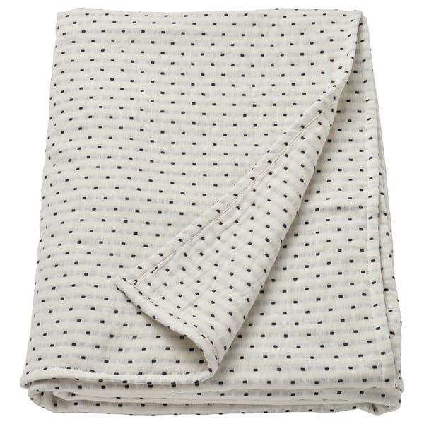 The JAKOBSLILJA bedspread. Its off-white with grey stitching, made of 100% cotton, designed for a double bed, rectangular shape, and folded neatly.