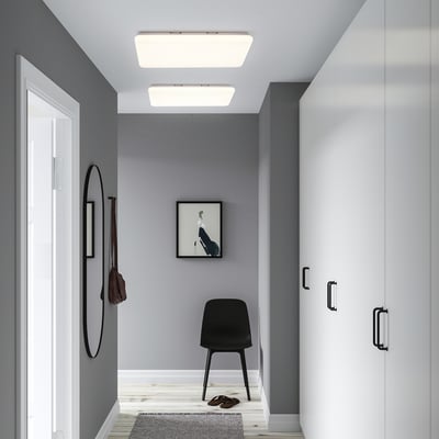 Modern grey entryway with two bright rectangular lights, black chair, wall hook, picture, mirror, and closet.
