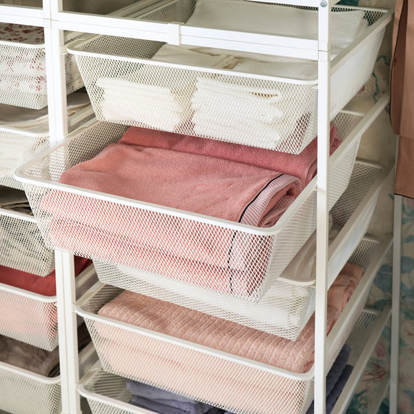 White JONAXEL mesh storage baskets in a closet, holding folded pink towels. Organised and functional design.