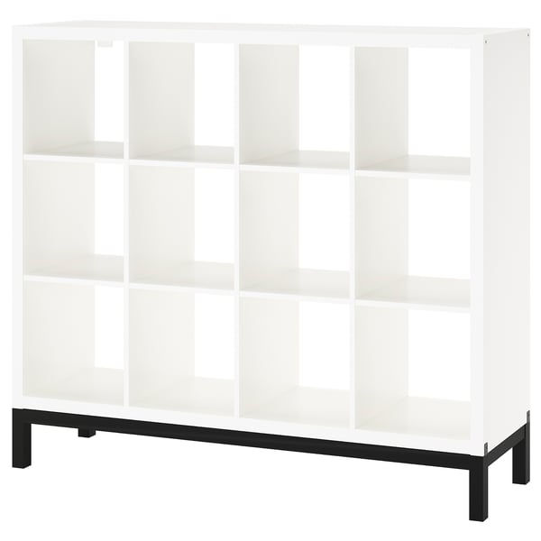 A white KALLAX shelving unit with a black metal base. It multiple open cubes for storage, designed to be airy and stylish.