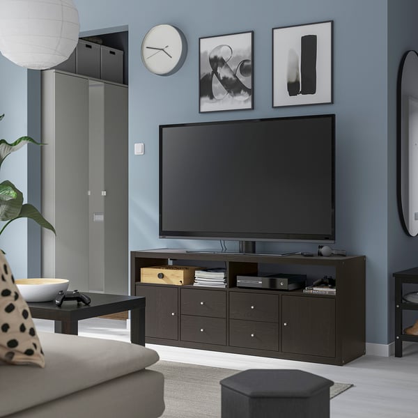 Modern living room with KALLAX tv stand, large tv, games, books. Grey sofa, coffee table, blue walls, artwork, clock.