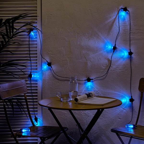 Blue lights decorate wall, illuminating minimalist outdoor table setup.