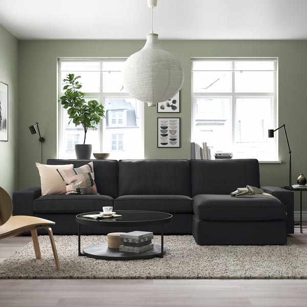 Modern living room with KIVIK dark grey sofa, large white pendant light, green walls, large windows, and decor items on a light rug.