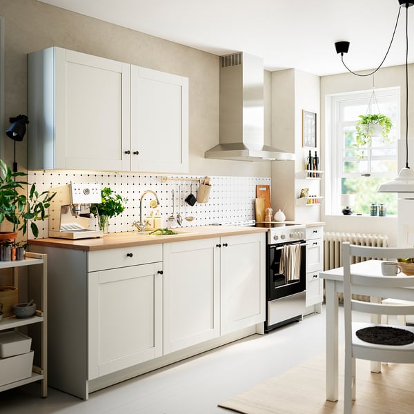 Modern white kitchen with oak countertop, featuring spacious cabinets, a stove, and sink, with accessories neatly displayed.
