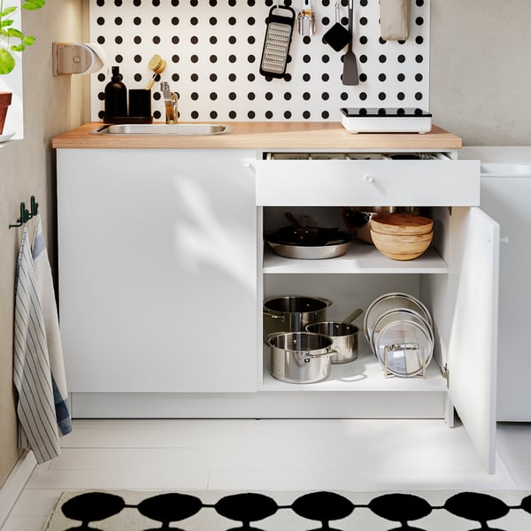 Wooden counter kitchen, open drawer with pots and pans, wall tools, black & white floor.