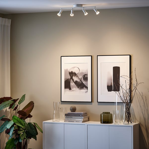 Modern living room with ceiling spotlights, art, and decorated sideboard.