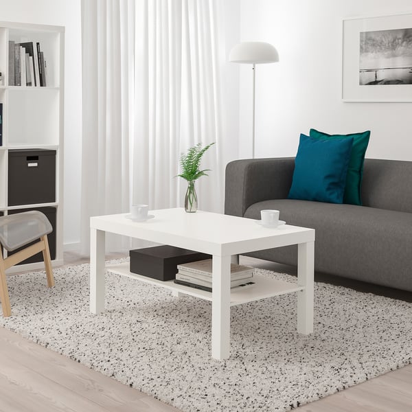 Modern living room with LACK coffee table between sofa and chair. Holds cups, plant, and books.