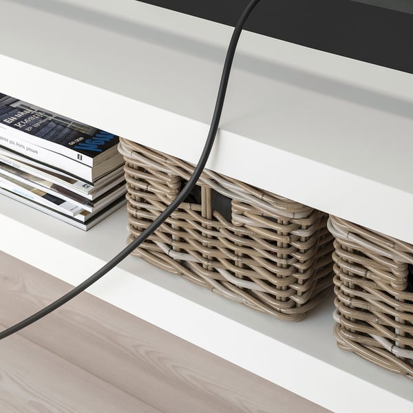 White LACK tv bench with woven baskets and stacked magazines, showcasing cable management through back opening.