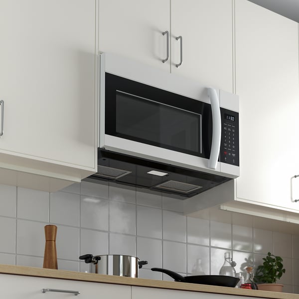 Modern kitchen with built-in microwave and extractor hood, digital display, black philtre, and accessories on countertop.