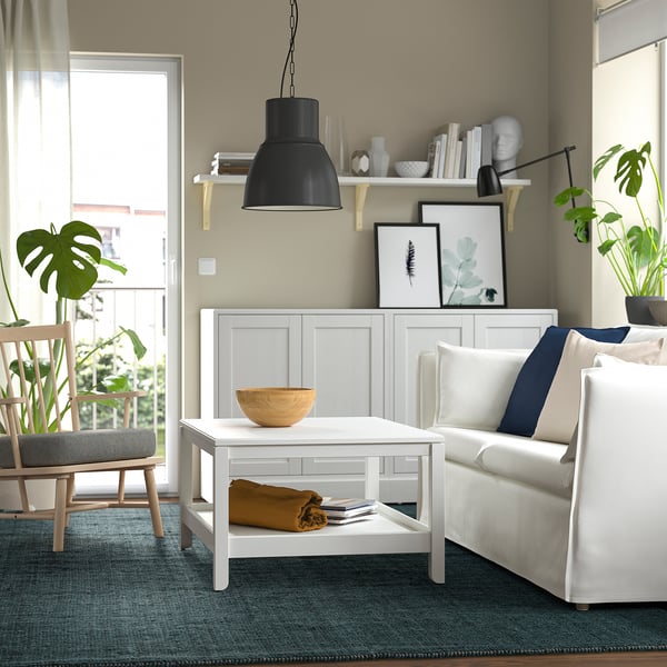 Modern living room with LANDBANA jute rug in dark blue. White coffee table, cosy couch, and plants. Black pendant lamp and natural decor.