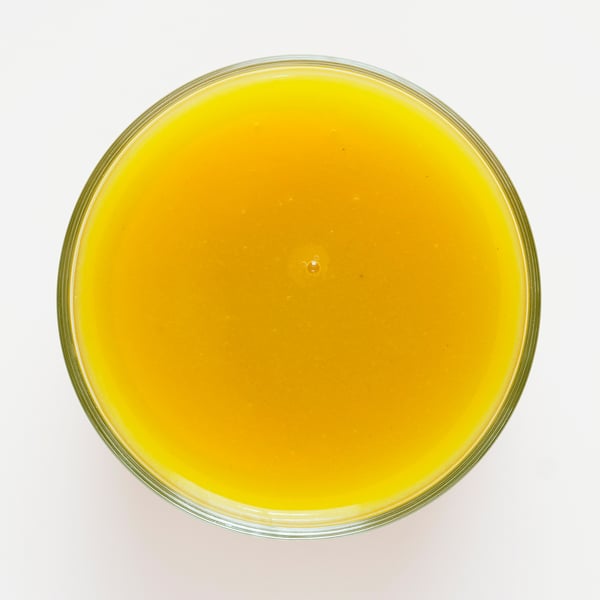 Bright orange smoothie in a glass container, likely made with mango, pumpkin, and apple.