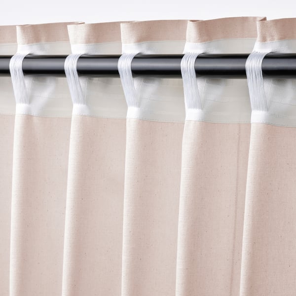 Light pink cotton curtains with header tape hang from a rod, featuring a textured weave and fullness for privacy and style.
