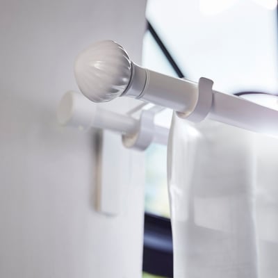Lerbonia white ceramic finial on curtain rod. Round ball shape, sleek design. Small compared to rod.