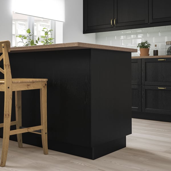 Modern black kitchen island, sleek surface, wood stools, white backsplash, big window.