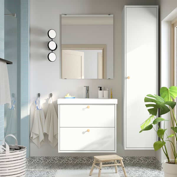 Modern bathroom with mirror, sink, shower, cabinet, plant.