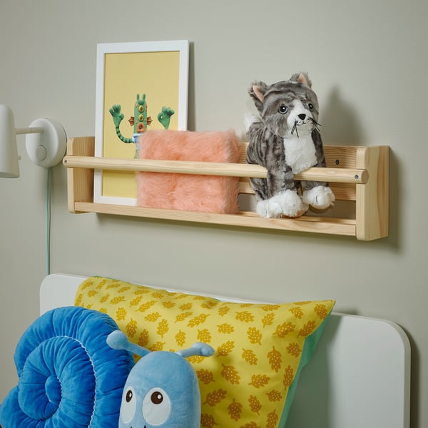 Wooden shelf with stuffed cat, bright pillow, blue cuddly toy above cosy bed.