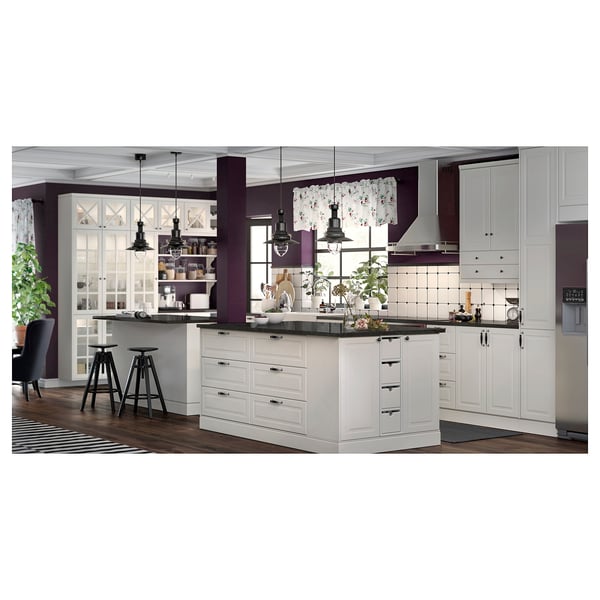 Modern kitchen with white cabinets, black countertops, black hanging lamps, and bar stools.