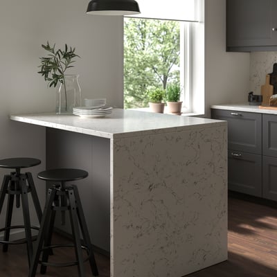 Small, modern kitchen island with LOCKEBO recycled glass countertop in white with black veining and adjustable black stools.